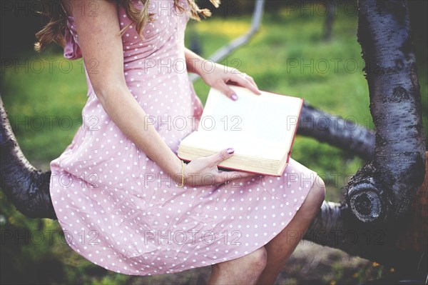 Close up of woman reading book in tree