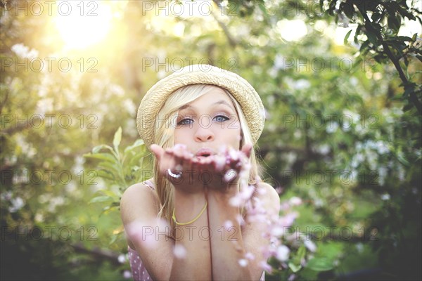 Woman blowing flower petals in garden