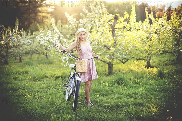 Woman pushing bicycle in rural field