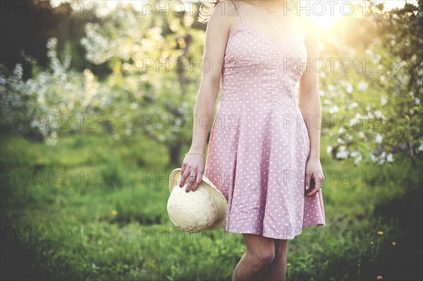 Woman holding hat in rural orchard