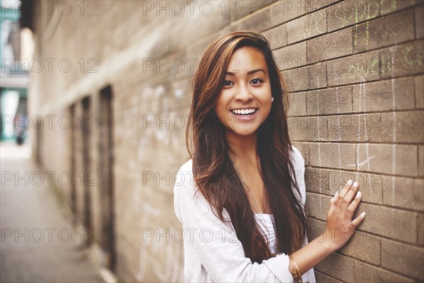 Woman standing at brick wall in city