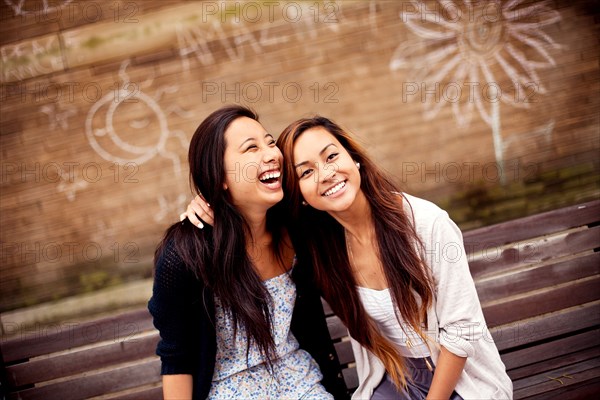 Women sitting on urban bench near graffiti wall