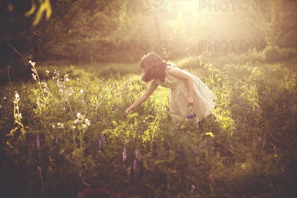 Girl picking flowers in rural field