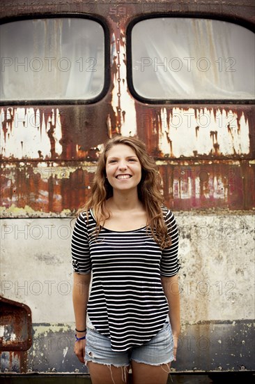 Smiling girl standing near dilapidated bus