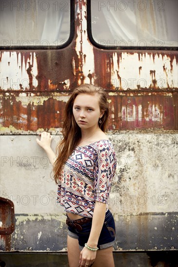 Caucasian girl standing near dilapidated bus