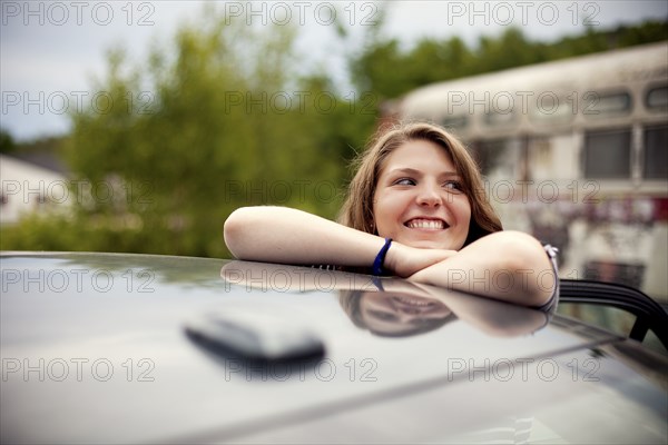 Smiling girl leaning on car roof