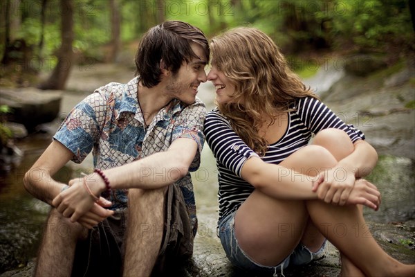 Couple touching foreheads on boulders in forest