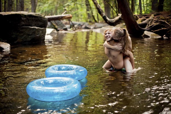 Man carrying girlfriend piggyback in forest river