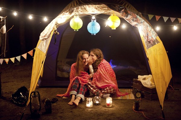 Girls whispering in camping tent at night