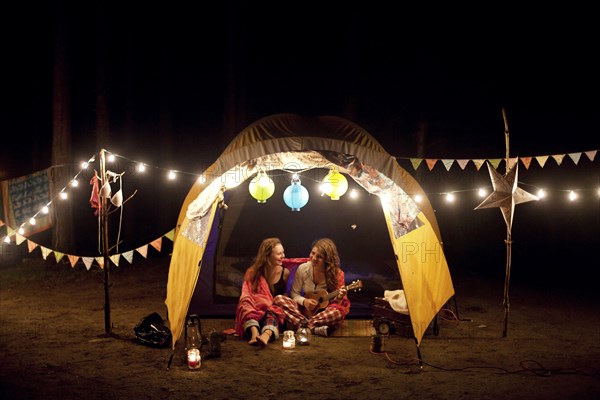 Girls relaxing in camping tent at night