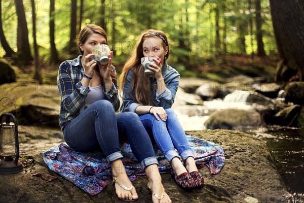Girls drinking coffee on forest rock