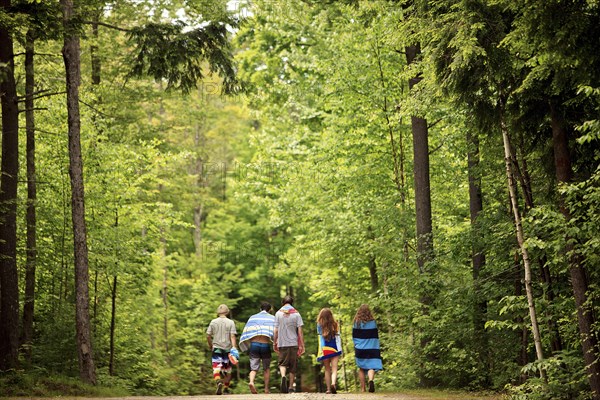 Friends walking on dirt path in forest