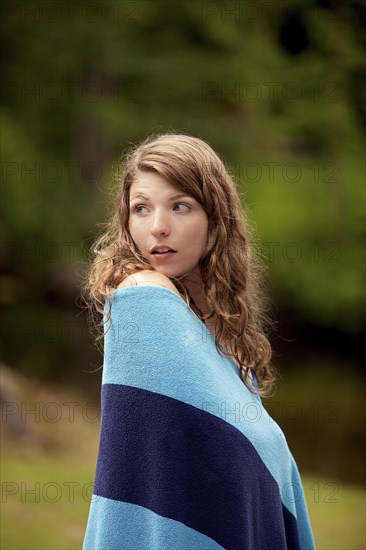 Girl wrapped in blanket in forest