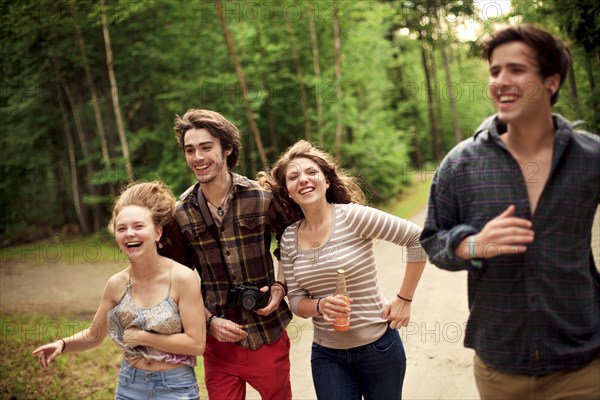 Friends running on dirt path in forest