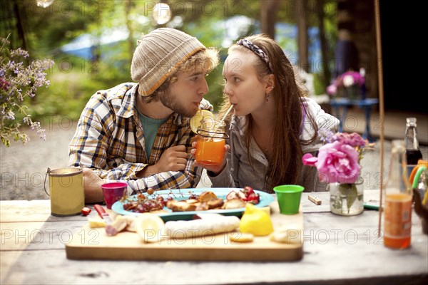 Couple sharing soda at picnic table in forest