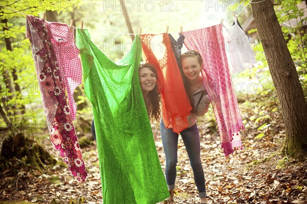 Girls hiding behind clothesline laundry in forest