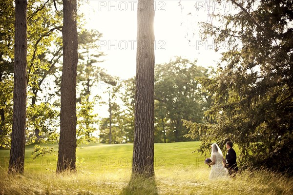 Bride and groom walking in rural field