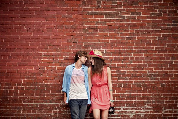 Couple leaning on brick wall