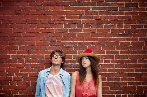 Couple leaning on brick wall