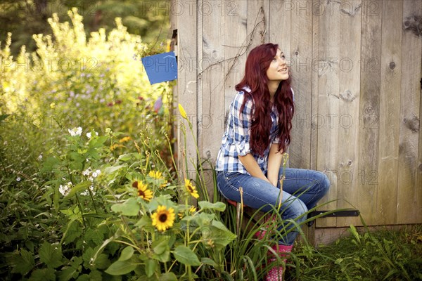 Gardener sitting near wooden shed in backyard