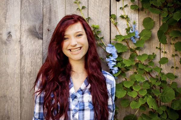 Woman smiling near wooden fence and ivy