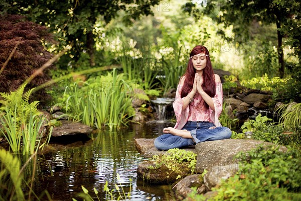 Girl meditating near rural creek