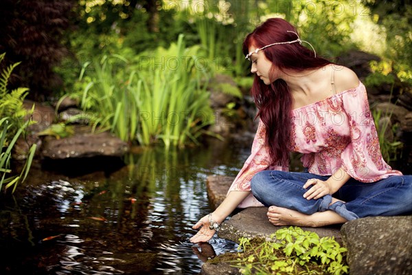 Girl meditating near rural creek