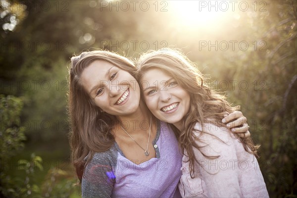 Smiling women hugging in rural field