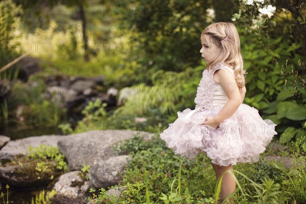 Girl in frilly dress exploring creek