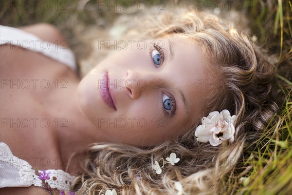 Close up of woman with blue eyes laying in grass