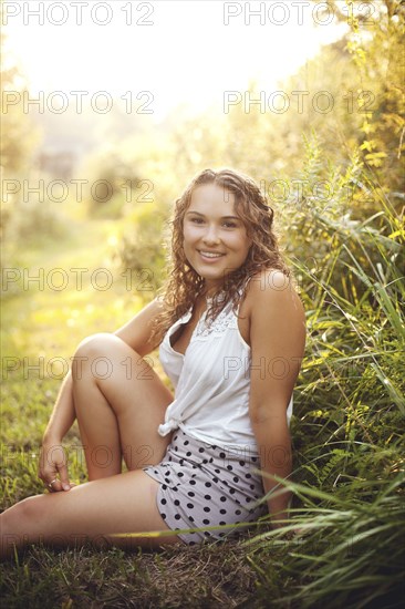 Smiling woman sitting in rural field