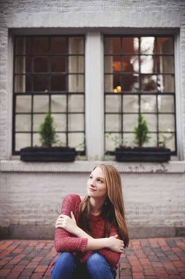 Girl sitting on brick sidewalk