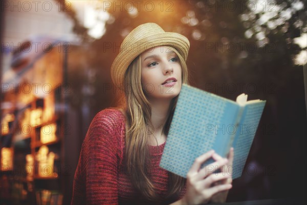 Girl reading book near window