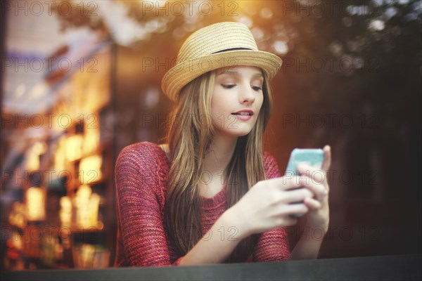 Girl using cell phone near window