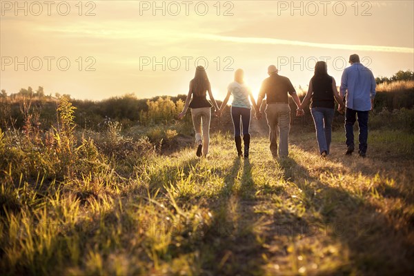 Friends holding hands in sunny rural field