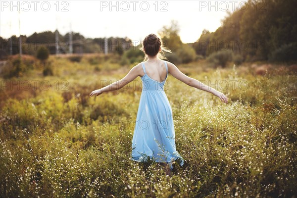 Girl walking with arms outstretched in rural field