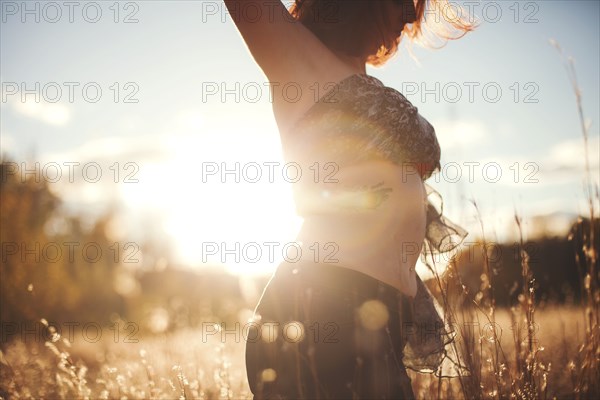 Woman dancing in tall grass in rural field