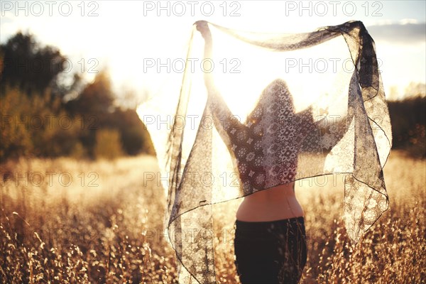 Woman playing with scarf in rural field