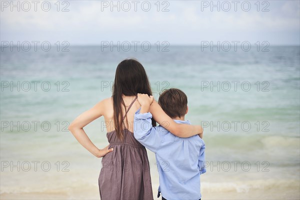 Brother and sister hugging on beach