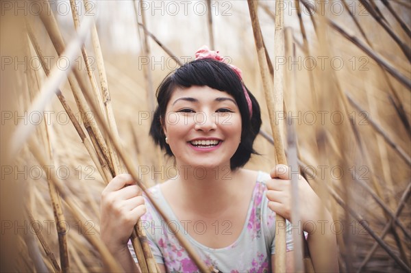 Smiling mixed race woman holding stalks in field