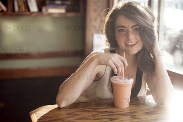 Caucasian teenage girl drinking smoothie in cafe