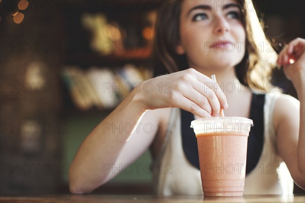 Caucasian teenage girl drinking smoothie in cafe