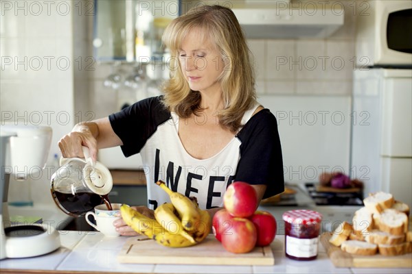 Caucasian woman pouring coffee in kitchen