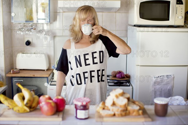 Caucasian woman drinking coffee in kitchen