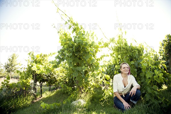 Caucasian farmer crouching in rural vineyard