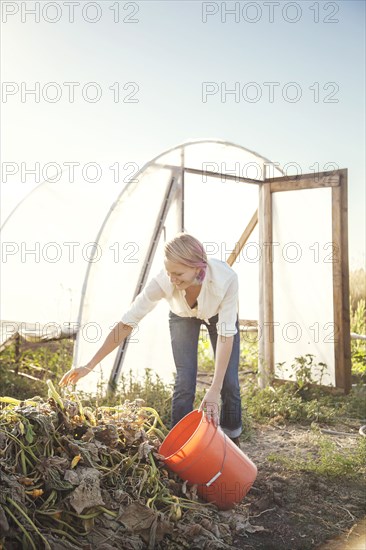 Caucasian farmer weeding plants in greenhouse