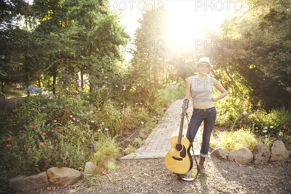 Caucasian musician holding guitar in park