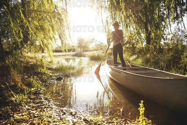 Caucasian woman rowing canoe in rural creek