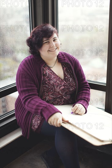 Caucasian artist holding easel in window