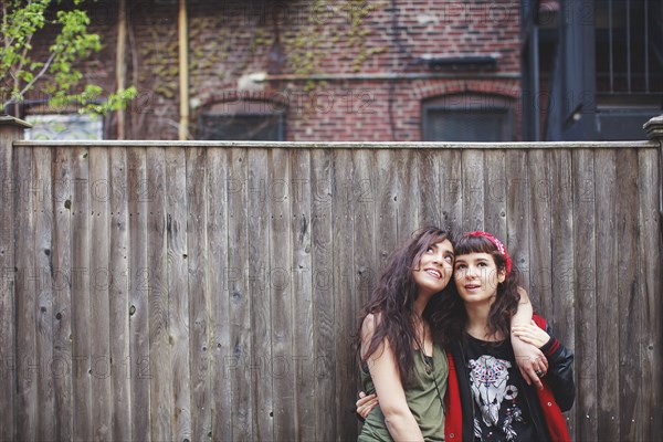 Friends hugging at wooden fence